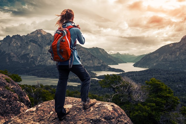 Excursionista con mochila mirando un lago glaciar en la cordillera de los Andes